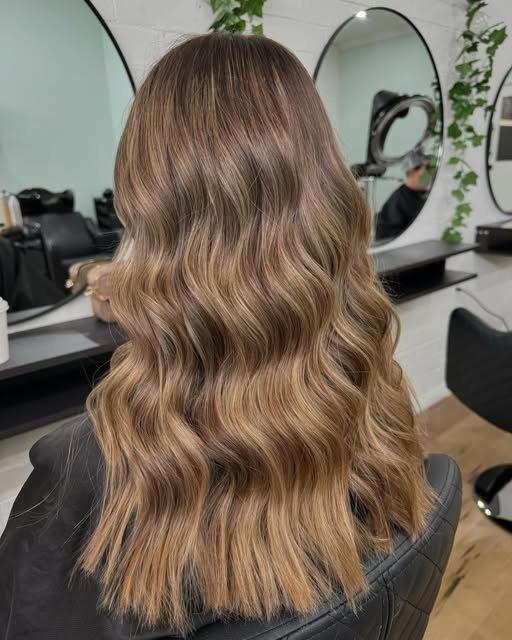 A warm caramel balayage finished in soft waves